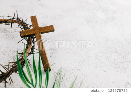 Palm Sunday setup with wooden cross, crown of thorns, and palm leaves on gray Palm Sunday setup with wooden cross, crown of thorns, and palm leaves on gray 123370723