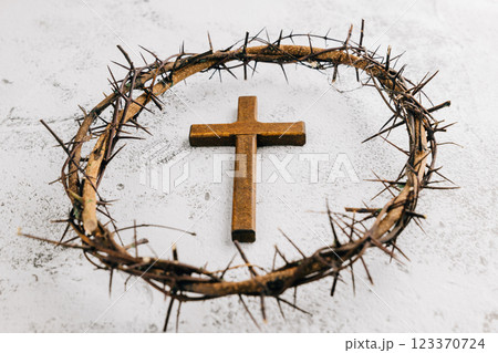 Wooden cross within a crown of thorns on light textured background for Palm Sunday. 123370724