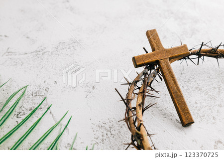 Palm Sunday setup with wooden cross, crown of thorns, and palm leaves on gray Palm Sunday setup with wooden cross, crown of thorns, and palm leaves on gray 123370725