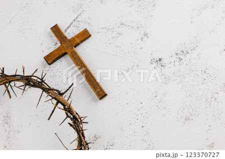 Wooden cross within a crown of thorns on light textured background for Palm Sunday. Wooden cross within a crown of thorns on light textured background for Palm Sunday. 123370727