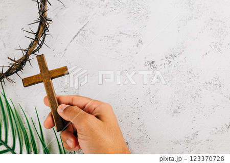 Hand holding cross and crown of thorns for Palm Sunday. Celebrating Easter faith Hand holding cross and crown of thorns for Palm Sunday. Celebrating Easter faith 123370728