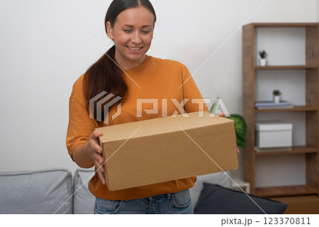 overjoyed woman holds a cardboard box, the embodiment of her online purchase contentment 123370811