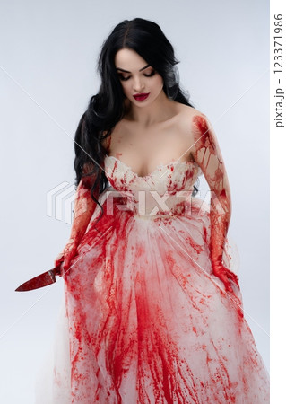 Bride in a blood-stained gown holds a knife, embodying beauty and terror 123371986