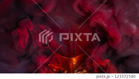 Shimmering cloud. Magical splash. Puff multicolor sparkling water emulsion streaming broken glass bulb. Glossy red paint surface abstract background. 123372580