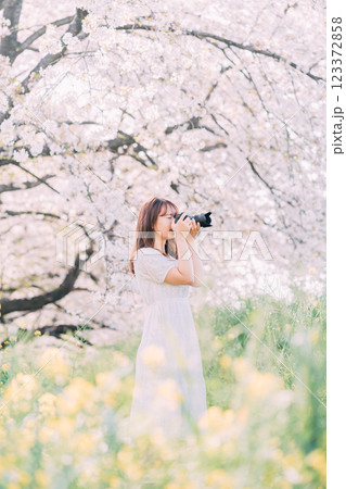 春の公園で菜の花を撮る女性 123372858