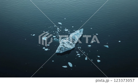 Aerial view of an iceberg and smaller pieces of ice floating on the surface of dark blue water, creating a serene and minimalist composition 123373057