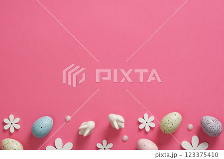Easter background with eggs, bunnies and wooden flowers on pink background. Place for your text. Easter background with eggs, bunnies and wooden flowers on pink background. Place for your text. 123375410