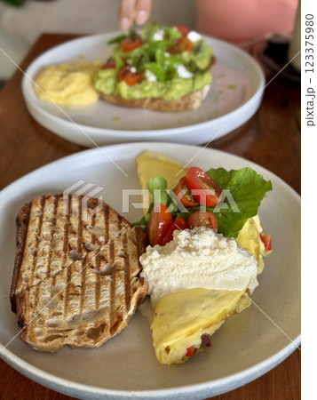 Breakfast with scrambled eggs, toast, sausage, cherry tomatoes, lettuce and avocado on a white plate 123375980