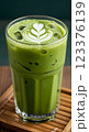 Glass of iced matcha latte with milk swirl effect, condensation on glass, served on a bamboo coaster, fresh green color 123376139
