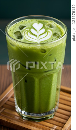 Glass of iced matcha latte with milk swirl effect, condensation on glass, served on a bamboo coaster, fresh green color 123376139