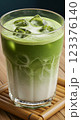 Glass of iced matcha latte with milk swirl effect, condensation on glass, served on a bamboo coaster, fresh green color 123376140