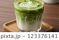 Glass of iced matcha latte with milk swirl effect, condensation on glass, served on a bamboo coaster, fresh green color 123376141