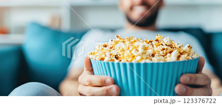 Relaxed man enjoying popcorn on couch, perfect for movie night 123376722