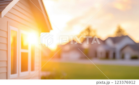 warm sunset illuminates row of houses, creating serene atmosphere with glowing windows. soft light enhances peaceful neighborhood scene 123376912