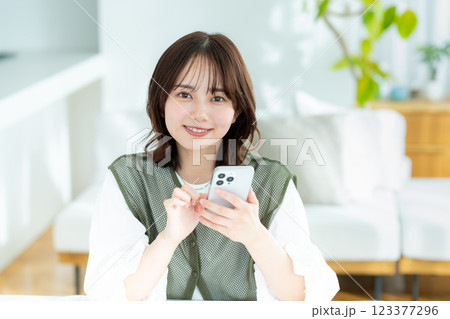 部屋でスマホを操作する若い女性 部屋でスマホを操作する若い女性 123377296