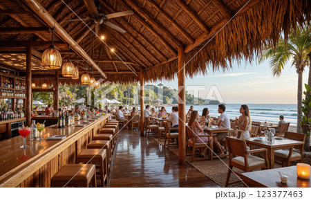 Tropical Beach Bar with Straw Roof and Ocean View A rustic tropical beach bar with a straw roof, guests sipping colorful cocktails while 123377463