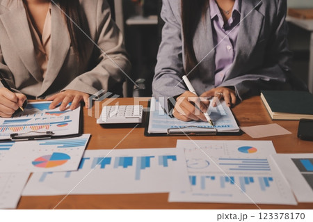 Group of confident business people point to graphs and charts to analyze market data, balance sheet, account, net profit to plan new sales strategies to increase production capacity. 123378170