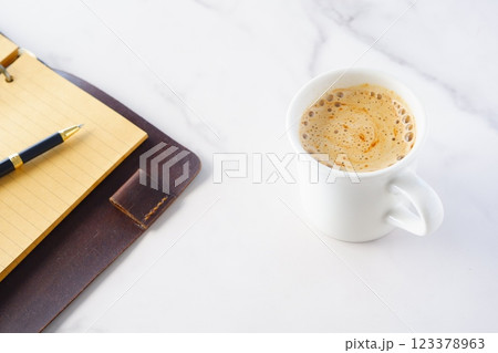 ミルクを入れたコーヒー、カフェ・ラッテを飲みながら、茶色の革のシステム手帳でデスクワーク中のイメージ 123378963