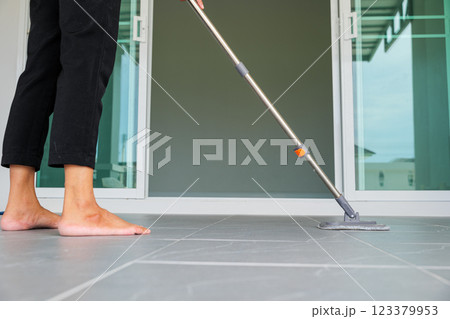 Asian woman mops the floor indoors, cleaning her outdoor front home with a mop and rag. Housewife maintaining a clean home. Represents the concept of professional housekeeping and house cleanup jobs 123379953