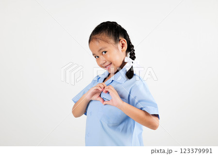 Portrait smile Asian little girl kindergarten holding hands together on chest in heart shape studio isolated white background, happy woman kid wear school uniform showing heart gesture, back to school 123379991