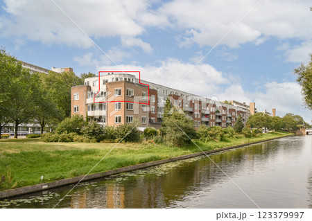 Contemporary residential architecture bordered by greenery and a tranquil water channel creates a serene urban environment. 123379997