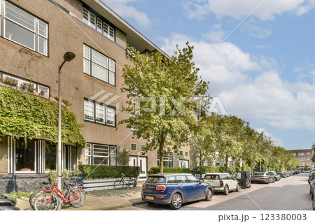 A serene urban street scene featuring neatly lined trees, parked cars, and modern architecture, conveying a peaceful residential atmosphere. A serene urban street scene featuring neatly lined trees, parked cars, and modern architecture, conveying a peaceful residential atmosphere. 123380003