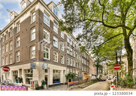 View of a picturesque street in Amsterdam featuring traditional architecture, lush greenery, and bicycle paths, highlighting the city's unique charm and urban landscape. View of a picturesque street in Amsterdam featuring traditional architecture, lush greenery, and bicycle paths, highlighting the city's unique charm and urban landscape. 123380034