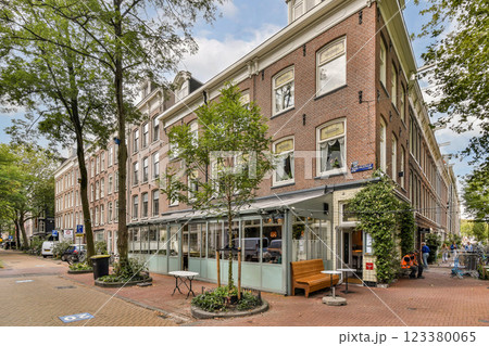 A picturesque street view featuring a quaint outdoor cafe, surrounded by lush greenery and classic architecture. Ideal for evoking a warm, inviting atmosphere. 123380065