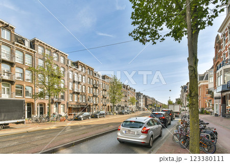 A picturesque urban scene showcasing a tree-lined street with parked cars and historic buildings, ideal for city exploration or architectural appreciation. A picturesque urban scene showcasing a tree-lined street with parked cars and historic buildings, ideal for city exploration or architectural appreciation. 123380111