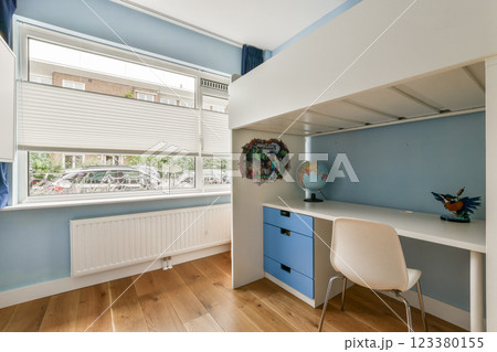 A bright and modern children's bedroom featuring a study space, playful colors, and large windows that invite natural light. 123380155