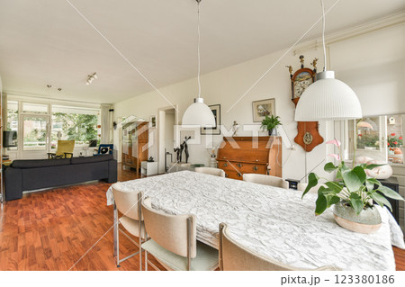 A spacious and bright dining area showcases a modern design, featuring a stylish table with chairs, plants, and warm wooden accents. A spacious and bright dining area showcases a modern design, featuring a stylish table with chairs, plants, and warm wooden accents. 123380186