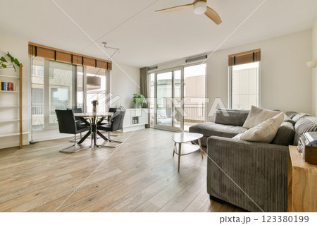 A bright and airy living room featuring large windows, a stylish sofa, and elegant furniture, creating a welcoming atmosphere perfect for relaxation. A bright and airy living room featuring large windows, a stylish sofa, and elegant furniture, creating a welcoming atmosphere perfect for relaxation. 123380199