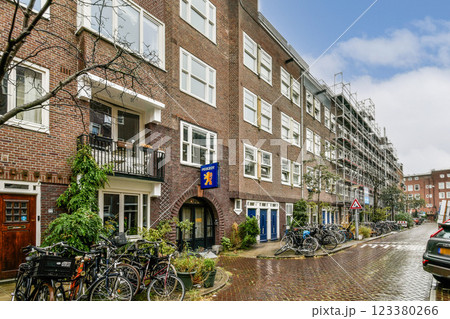 An inviting urban street scene featuring a row of residential buildings, greenery, and parked bicycles, depicting a cozy yet vibrant neighborhood. 123380266