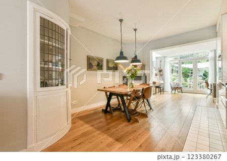 Stylish dining area featuring a wooden table, contemporary chairs, and large windows for ample natural light, creating a warm atmosphere. 123380267