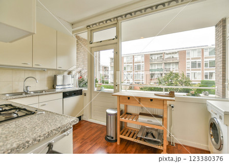 A spacious kitchen featuring modern appliances, ample counter space, and a large window offering a view of greenery outside, creating a welcoming atmosphere. A spacious kitchen featuring modern appliances, ample counter space, and a large window offering a view of greenery outside, creating a welcoming atmosphere. 123380376