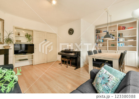 Spacious modern living room featuring a stylish bookshelf, elegant piano, and cozy seating arrangement, perfect for relaxation and reading time. 123380388