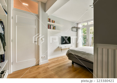 A contemporary bedroom showcasing wooden flooring, a minimalist aesthetic, and abundant natural light from large windows creating a serene atmosphere. A contemporary bedroom showcasing wooden flooring, a minimalist aesthetic, and abundant natural light from large windows creating a serene atmosphere. 123380421