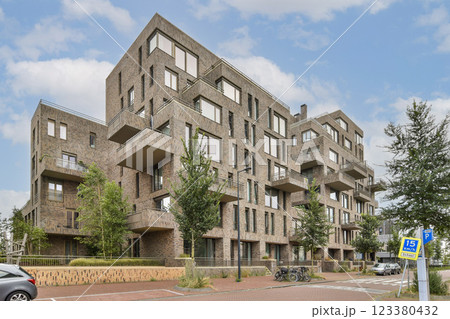 A stylish modern architectural complex featuring multiple residential units, large windows, and surrounding greenery in an urban setting. 123380432