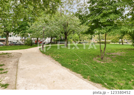 A tranquil pathway curves through a verdant park, lined with vibrant trees and well-maintained grass, inviting leisurely strolls and peaceful reflections. A tranquil pathway curves through a verdant park, lined with vibrant trees and well-maintained grass, inviting leisurely strolls and peaceful reflections. 123380452
