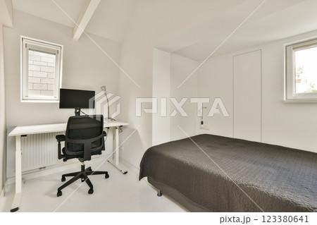 A sleek and minimalistic home office featuring a simple desk, ergonomic chair, and natural light from large windows. The aesthetic promotes productivity and focus. A sleek and minimalistic home office featuring a simple desk, ergonomic chair, and natural light from large windows. The aesthetic promotes productivity and focus. 123380641