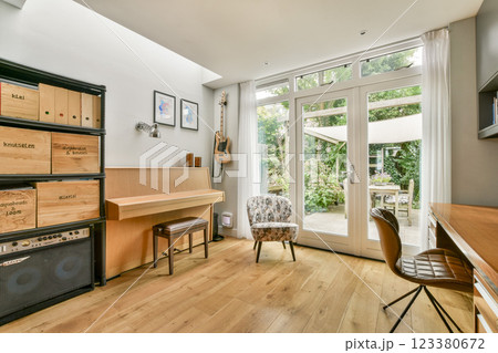 A bright and inviting interior featuring wooden floors, contemporary furniture, and large windows that create a seamless connection with the outdoors. 123380672