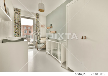 A stylish baby room featuring minimalistic decor, a crib, and ample natural light. The soft color palette and modern furniture create a cozy atmosphere. 123381035
