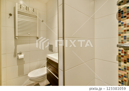 A sleek and contemporary shower space featuring white tiles, a stylish towel rack, and a colorful mosaic accent wall that adds vibrancy to the design. A sleek and contemporary shower space featuring white tiles, a stylish towel rack, and a colorful mosaic accent wall that adds vibrancy to the design. 123381059