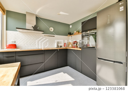 A stylish and contemporary kitchen featuring sleek black cabinetry, a wooden countertop, and modern appliances, promoting a bright and functional cooking space. 123381068