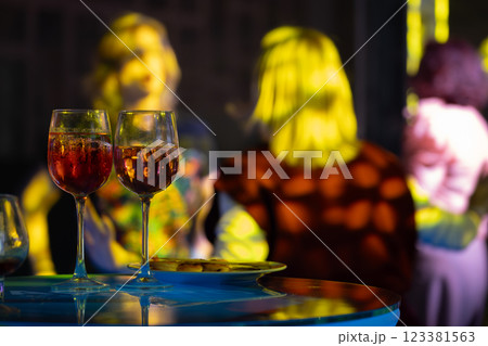 Two wine glasses on table during social gathering with colorful lighting 123381563