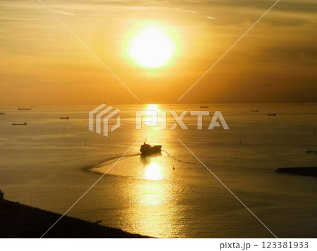 沈む夕日に向かって進む船 123381933