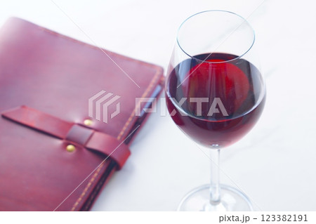 赤ワインを飲みながら、ワインレッドの革のシステム手帳に日記をつけているイメージ 123382191