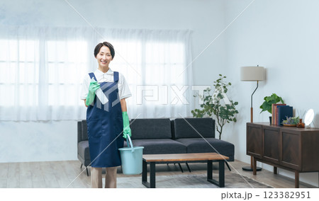 リビングルームで清掃道具を持つミドル女性 リビングルームで清掃道具を持つミドル女性 123382951