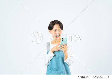 スマホを使うエプロンをつけたミドル女性 123382983