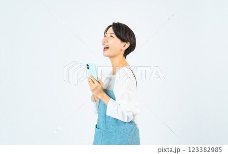 笑顔でスマホを使うエプロンをつけたミドル女性 123382985